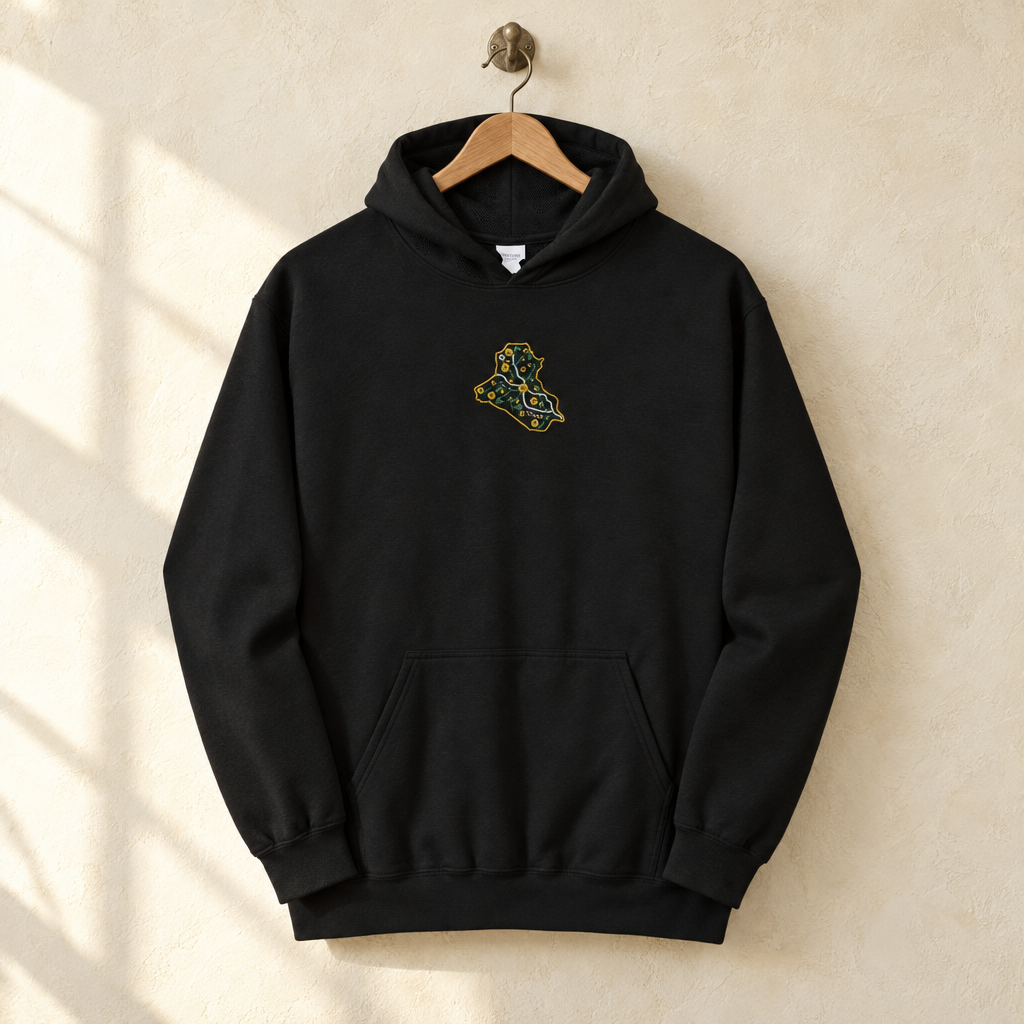 Embroidered Iraq Hoodie, hanging on a wooden hanger against a pale wall.