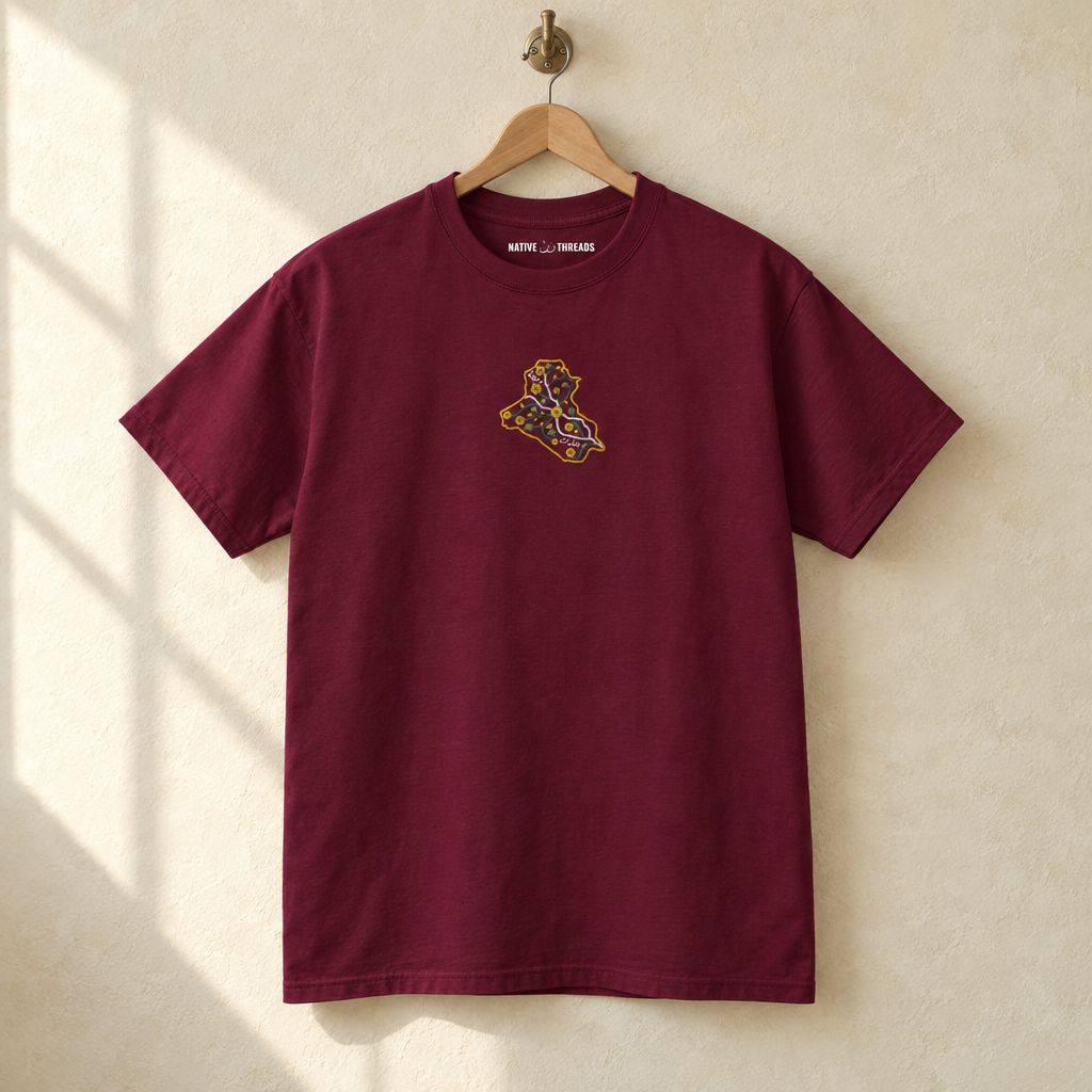 Embroidered Iraq T-shirt, hanging on a wooden hanger against a pale wall.