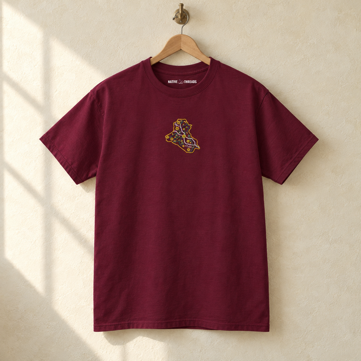 Embroidered Iraq T-shirt, hanging on a wooden hanger against a pale wall.