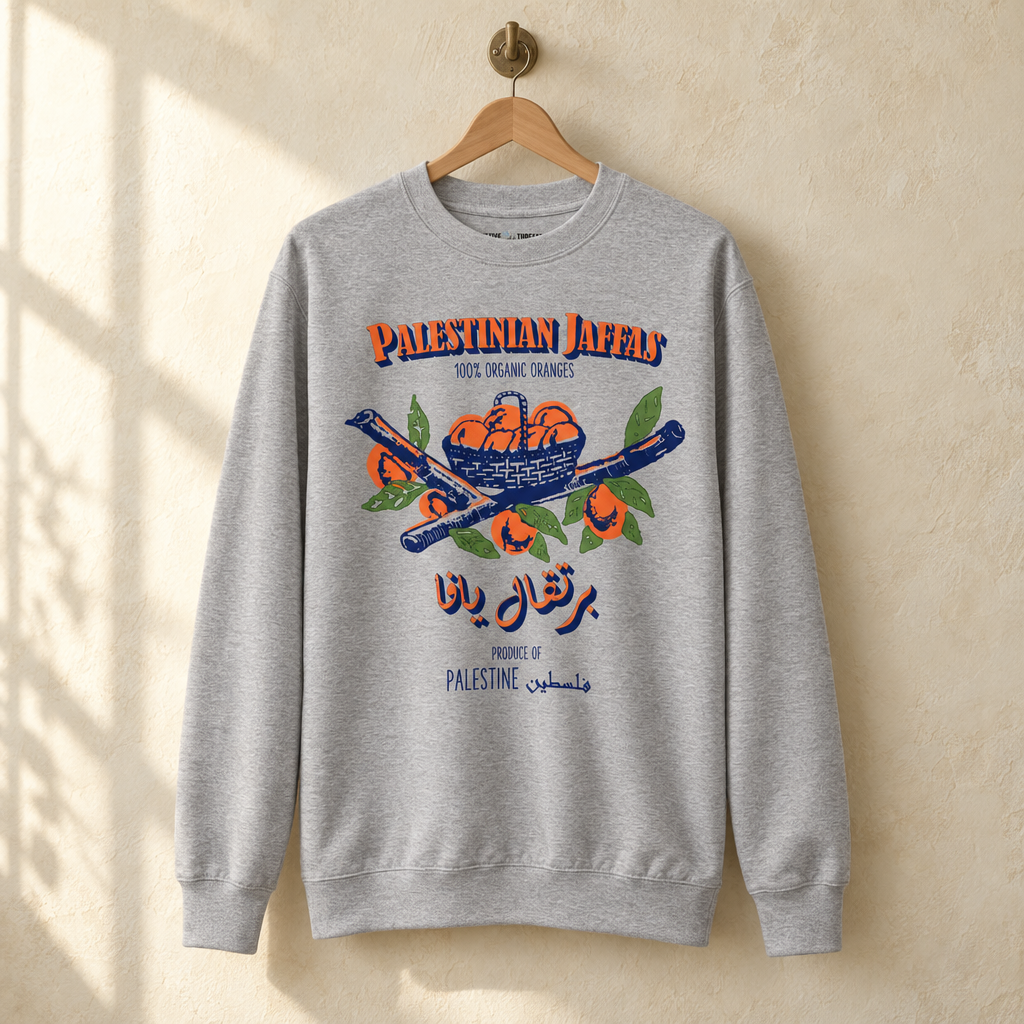 Palestinian Jaffas Sweater, hanging on a wooden hanger against a pale wall.