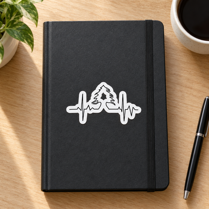 Lebanese Heart Beat Sticker, applied to a plain notebook on a desk.