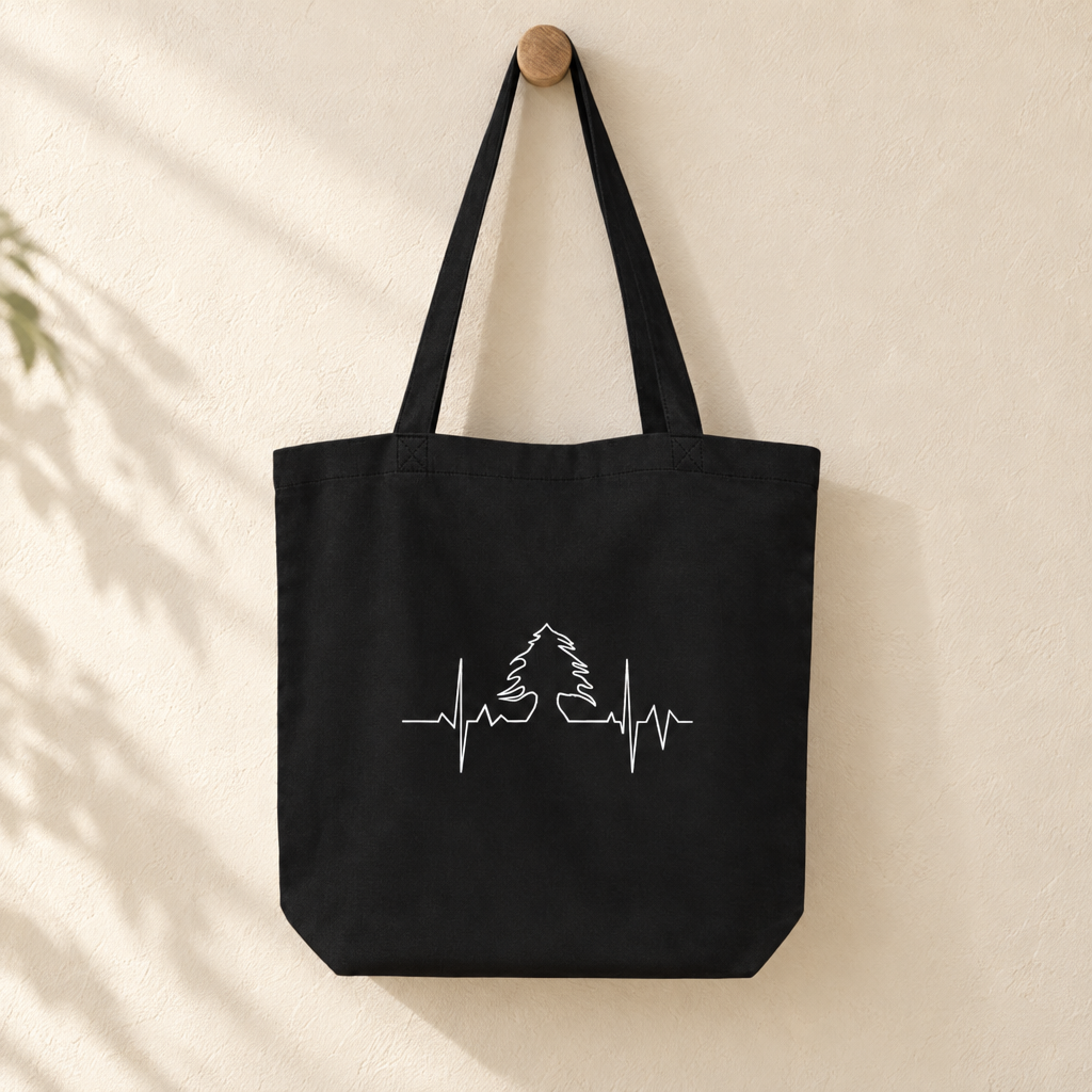 Lebanese Heart Beat Tote Bag, hanging from a wooden peg with the printed front visible.
