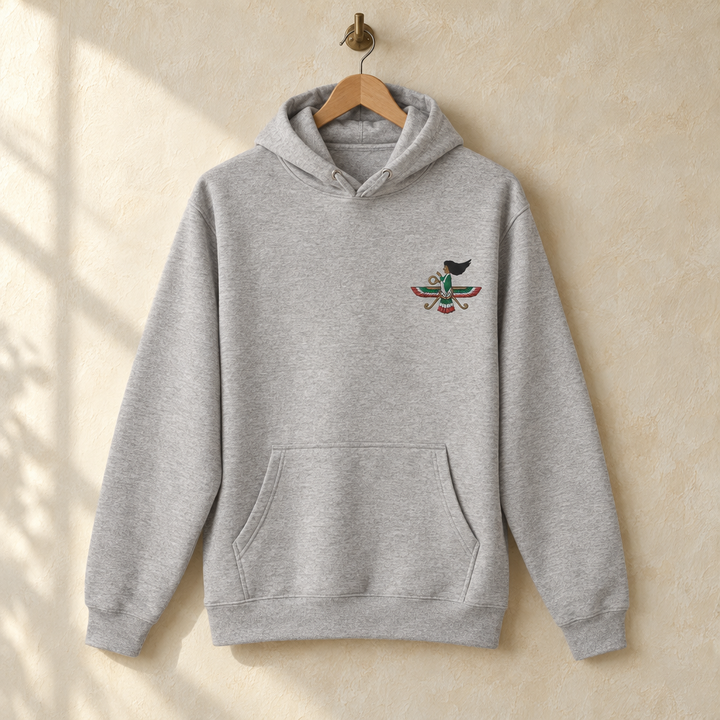 Limited Edition Embroidered Iranian Farvahar Hoodie, hanging on a wooden hanger against a pale wall.