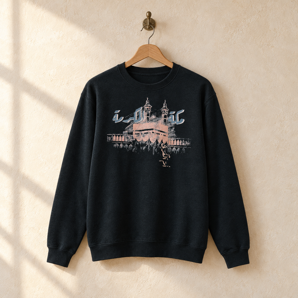 Makkah al-Mukarramah Sweater, hanging on a wooden hanger against a pale wall.