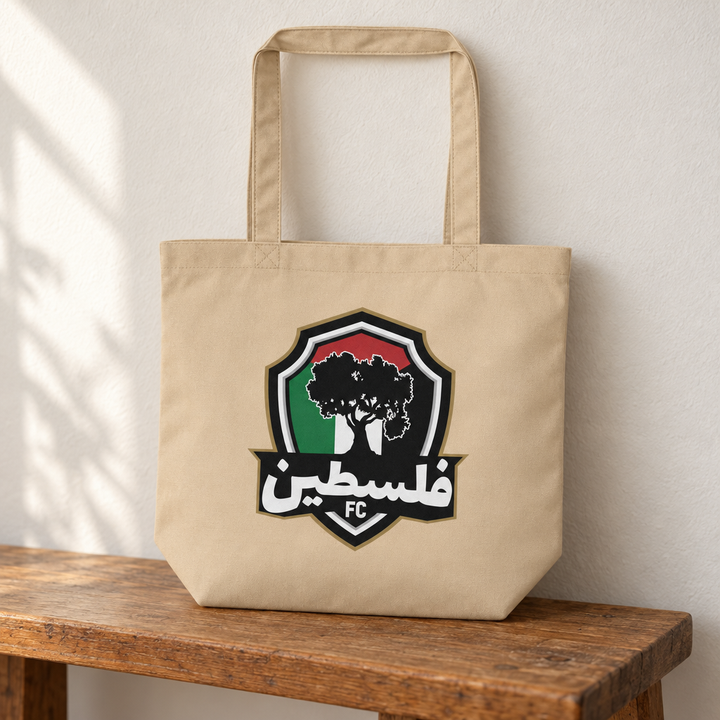 Palestine FC Eco Tote Bag, standing on a wooden bench with the printed front visible.
