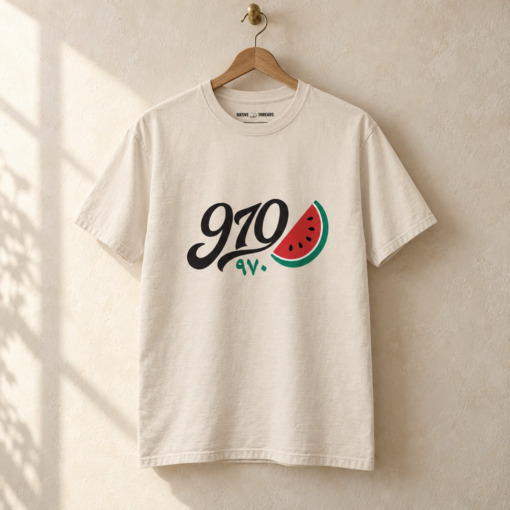 Palestine Watermelon Area Code T-shirt, hanging on a wooden hanger against a pale wall.
