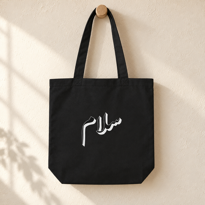 Salam Tote Bag, hanging from a wooden peg with the printed front visible.