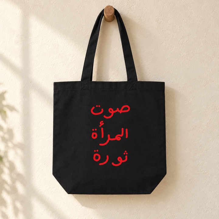 Women Revolution Tote Bag, hanging from a wooden peg with the printed front visible.